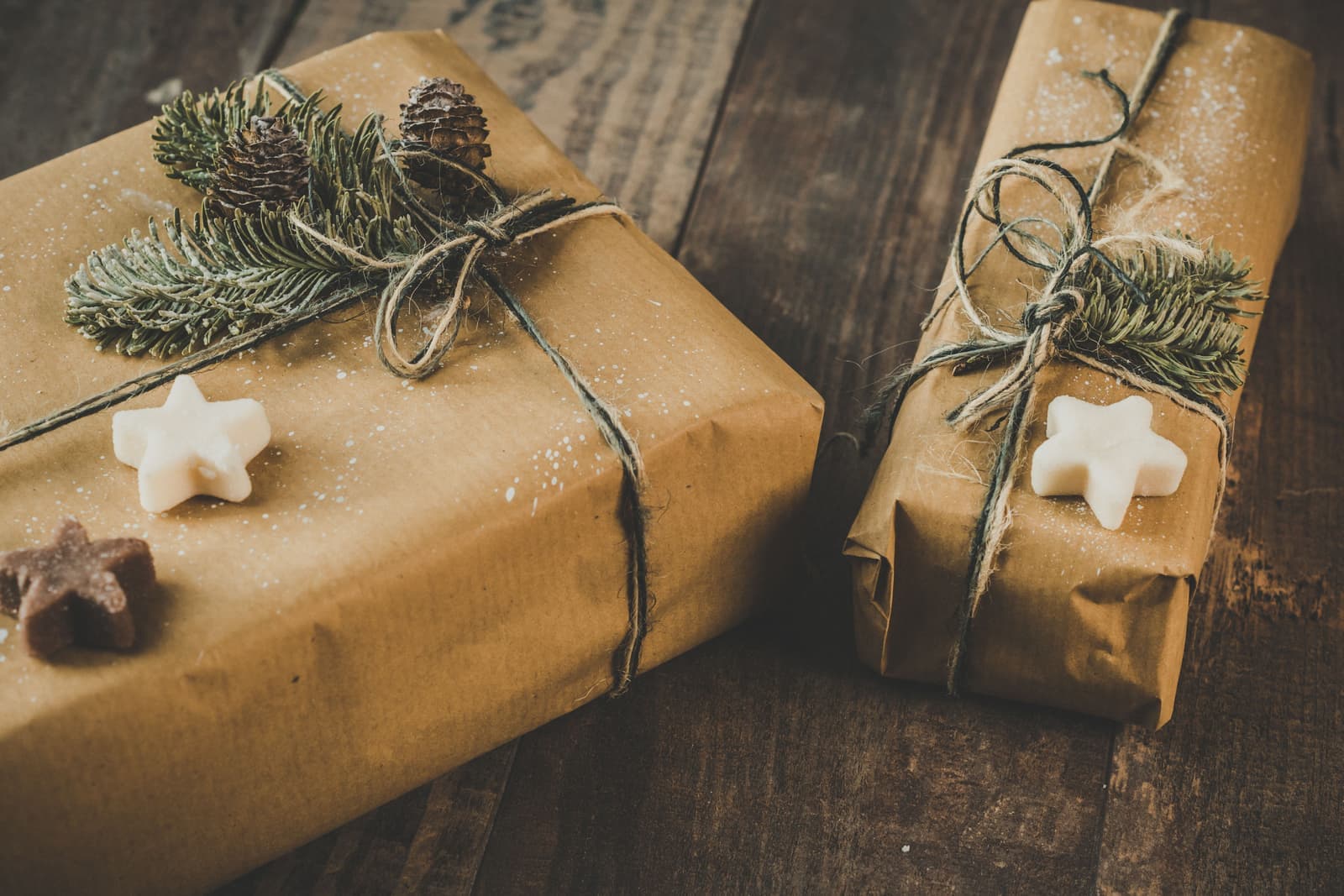 Two presents wrapped in brown paper and twine on a dark wooden table