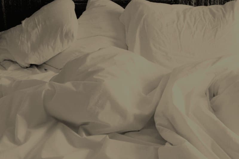 Pillows stacked on a bed in soft lamplight